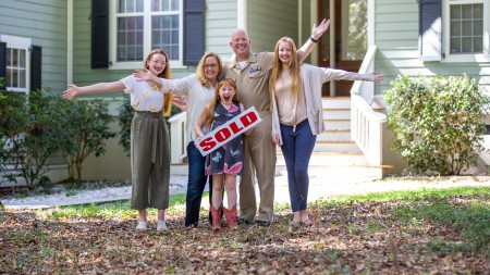 Family posing together in front of their home