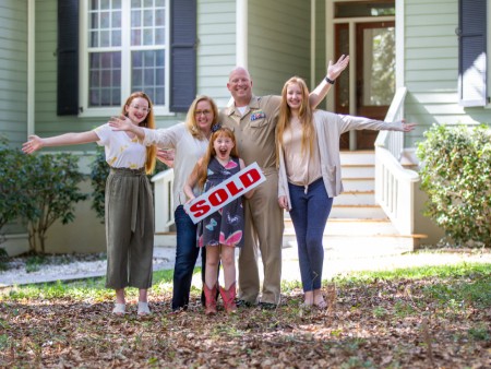 Family posing together in front of their home