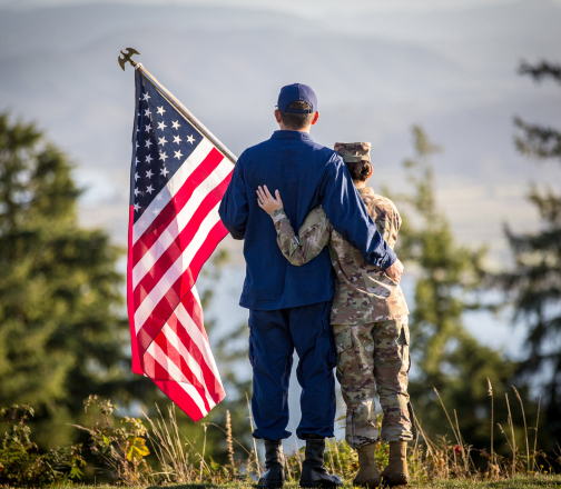Service member couple holding an American flag