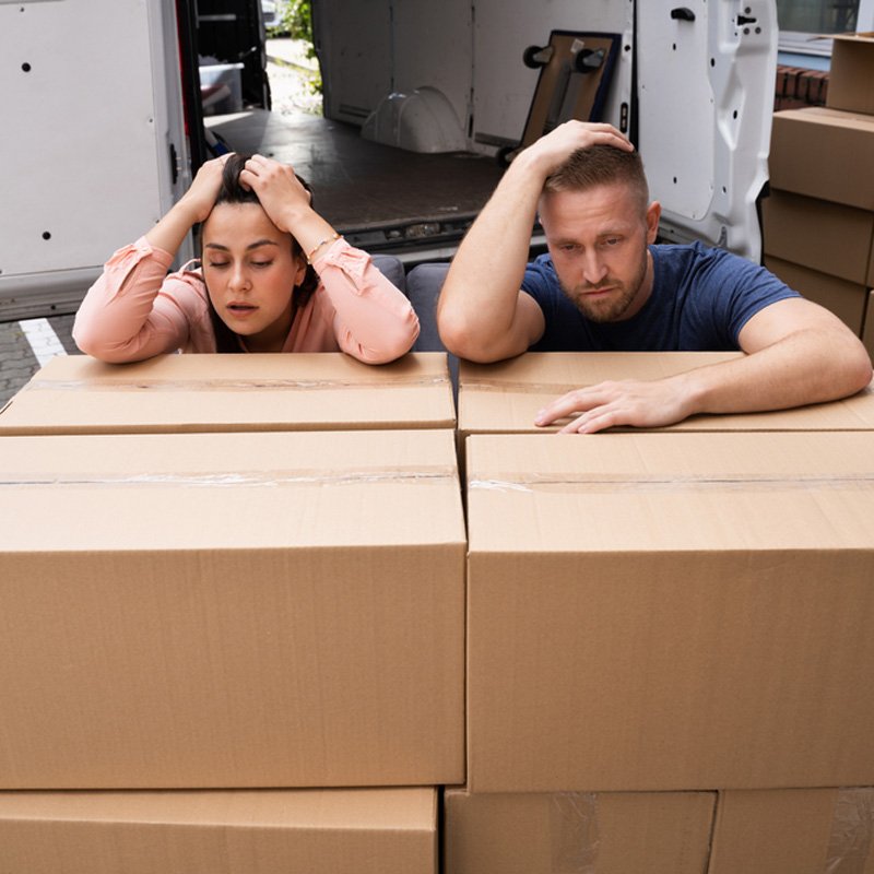 Frustrated movers resting on cardboard box