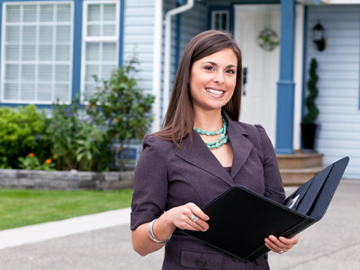 Smiling Realtor holding Padfolio in front of Home