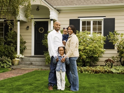 Smiling family posing together in front of their home