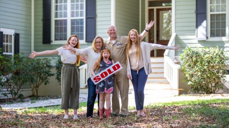 Family posing together in front of their home