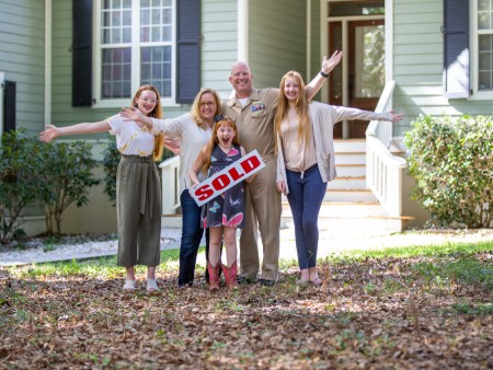 Family posing together in front of their home