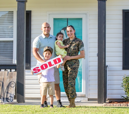 Family on doorstep holding sold sign