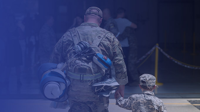 Military member walking hand-in-hand with his son