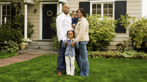 Smiling family posing together in front of their home